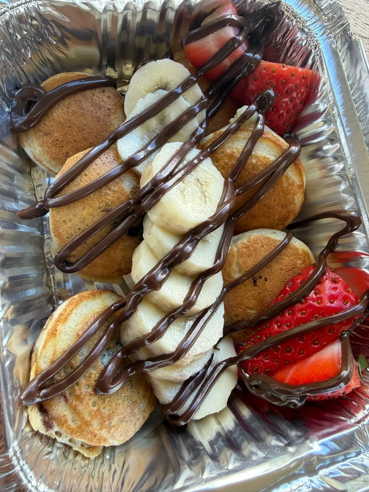 Mini pancakes topped with strawberries, banana and chocolate sauce
